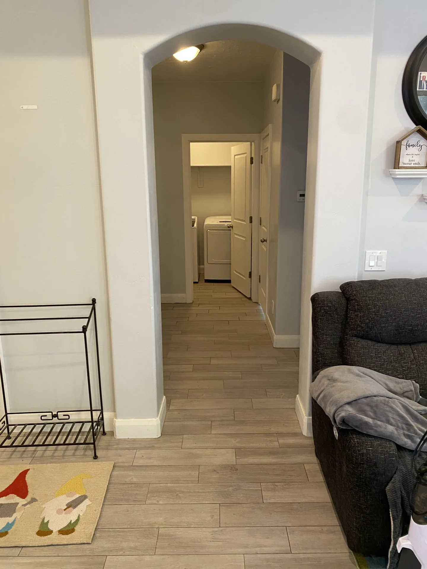 Finished hallway with arched doorway — new wood-look plank tile running through to laundry room