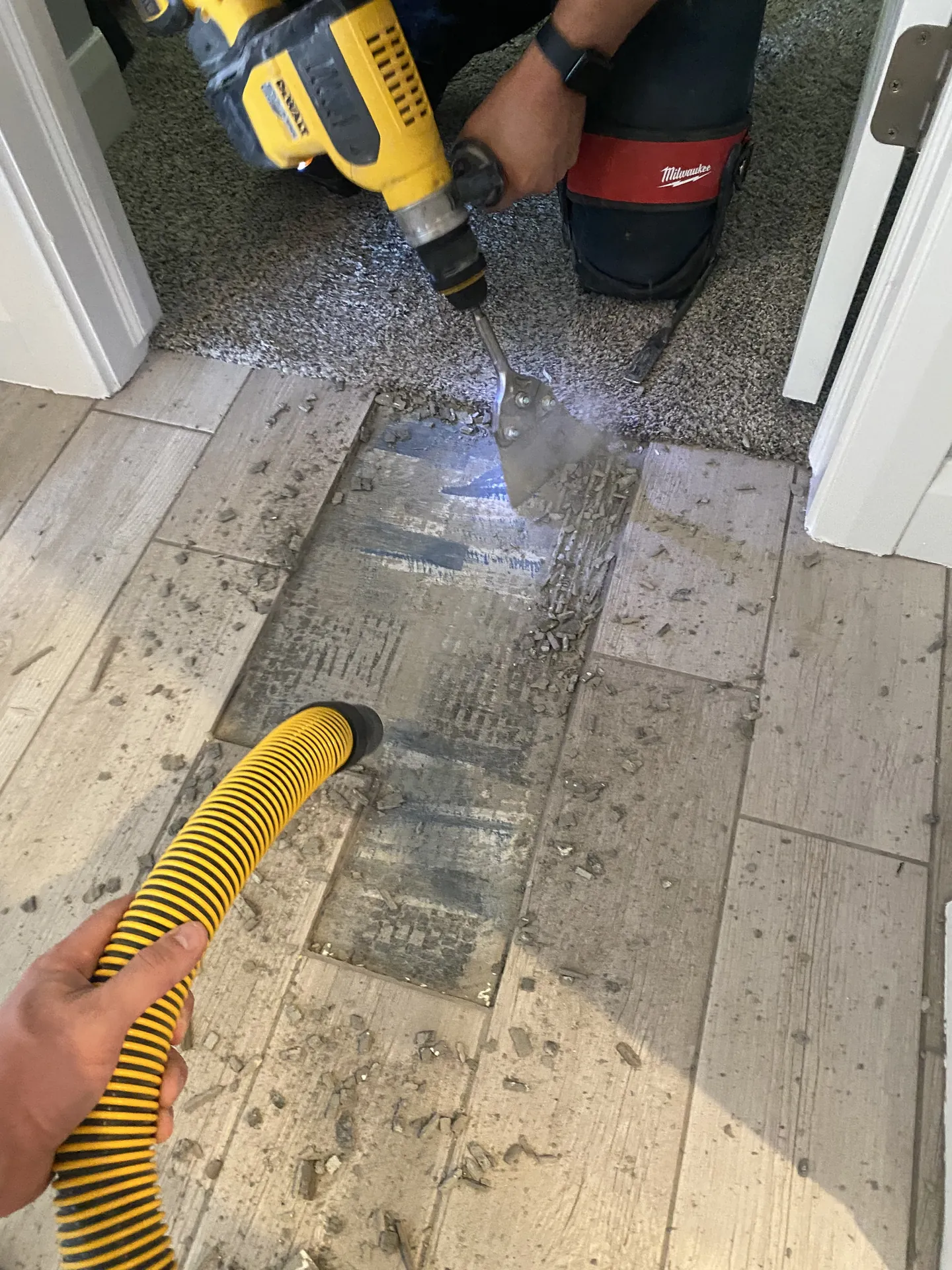 Close-up of tile demo — DeWalt rotary hammer chiseling tile with vacuum dust collection