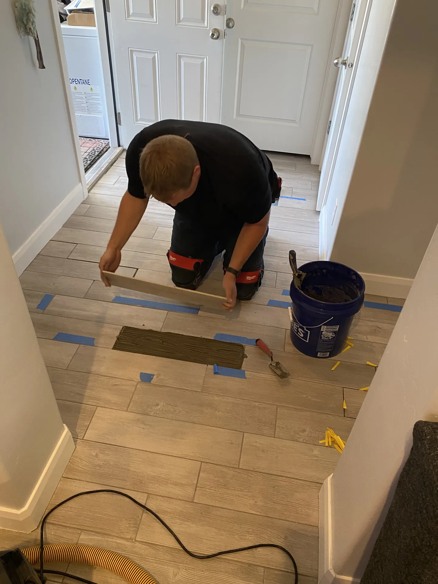Viking Solutions installer laying wood-look plank tile with thinset mortar and tile spacers