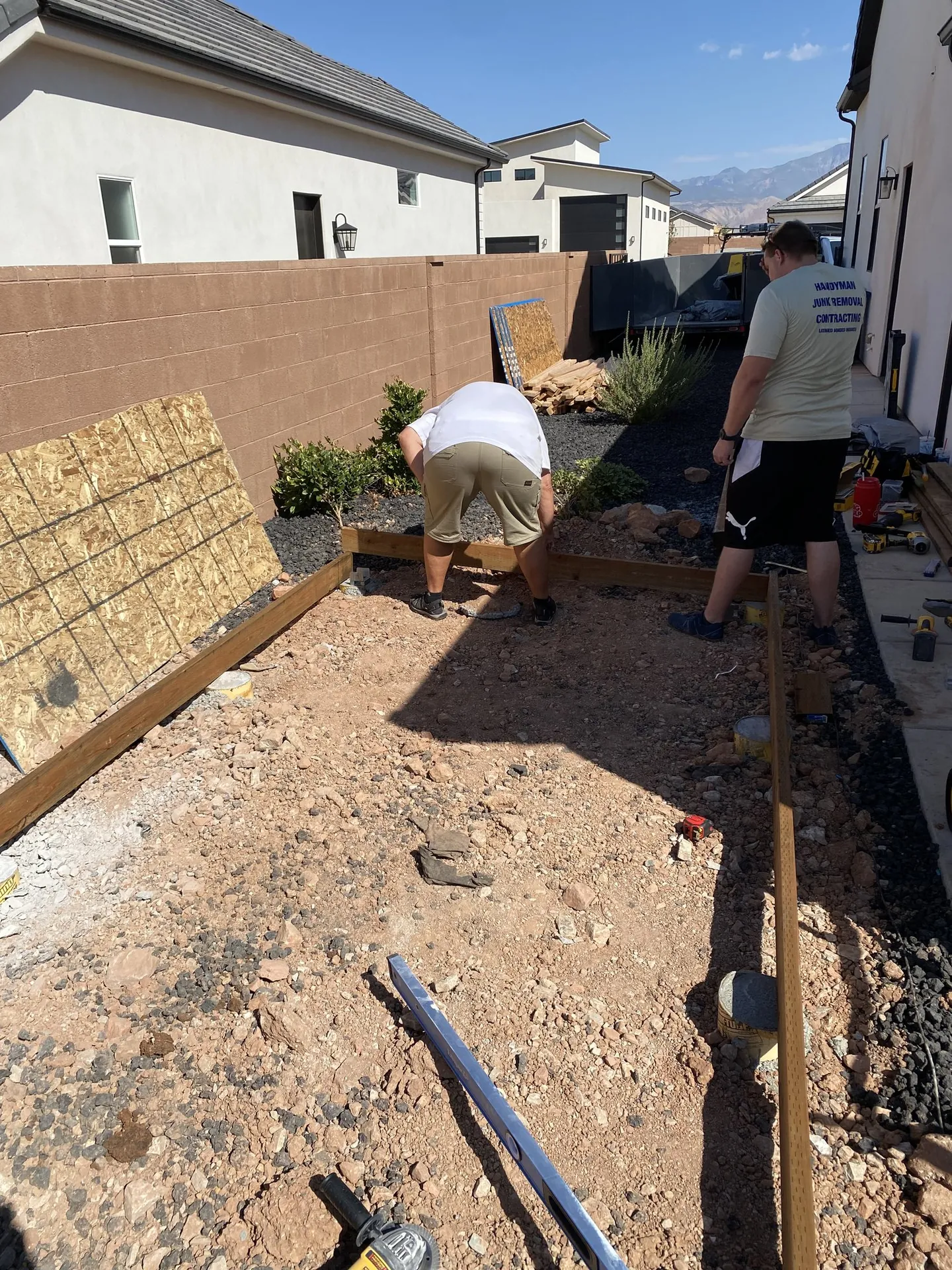 Two crew members laying out the shed floor frame over the pier footings