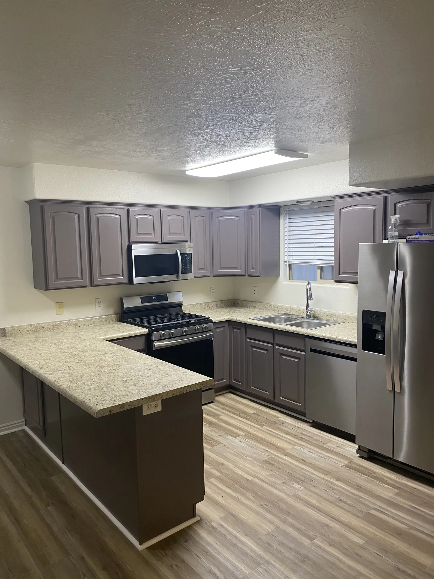 Finished apartment kitchen in St. George with gray painted cabinets and new LVP flooring after the remodel