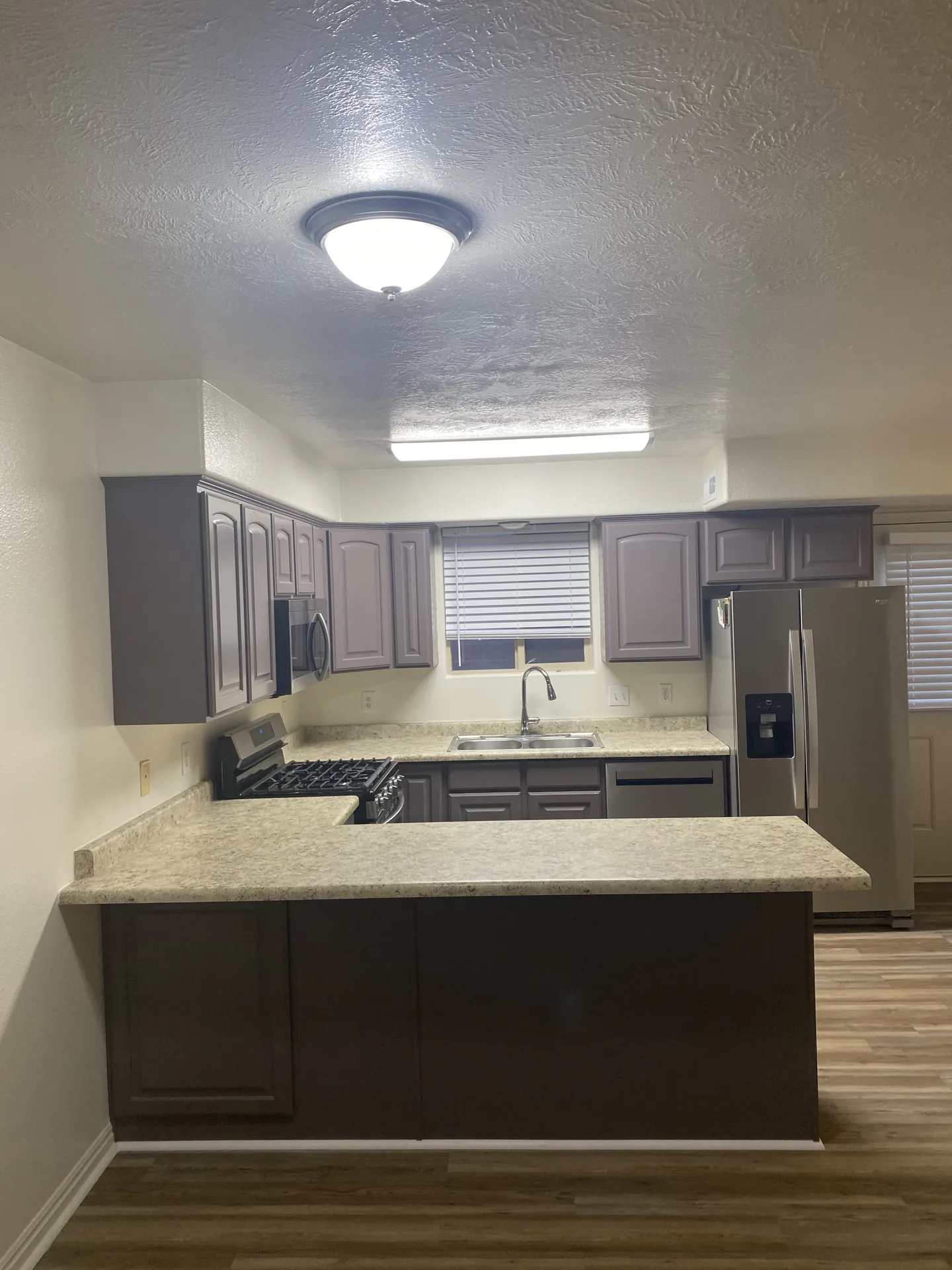 Wide view of the finished kitchen with gray cabinets, new counters area, and consistent LVP flooring