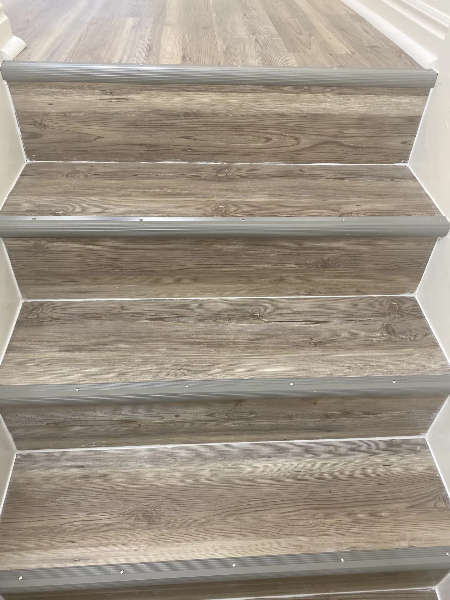 Detail of new LVP flooring installed on the apartment stairs replacing old carpet