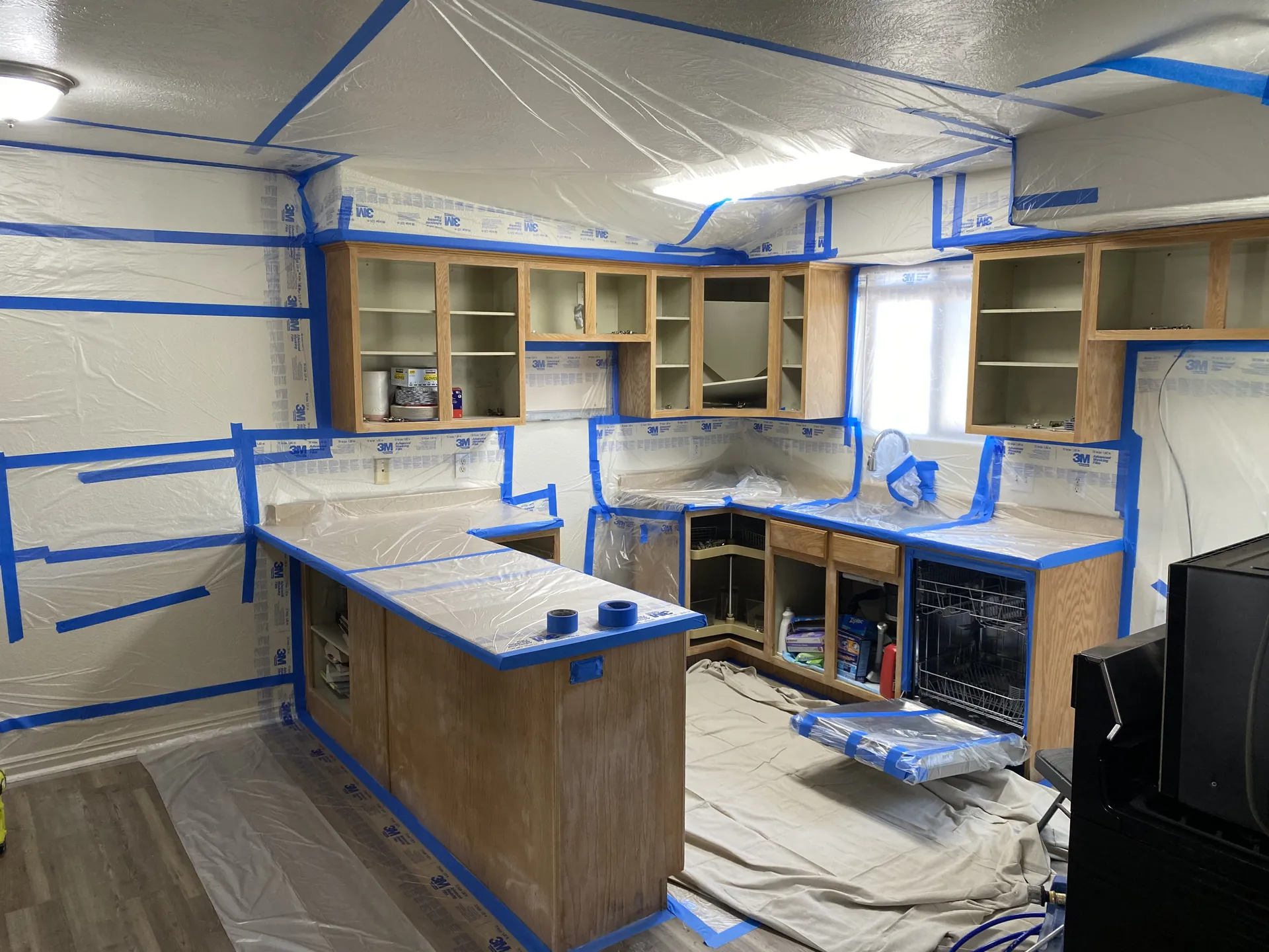 Kitchen fully masked with plastic and paper before cabinet spray painting