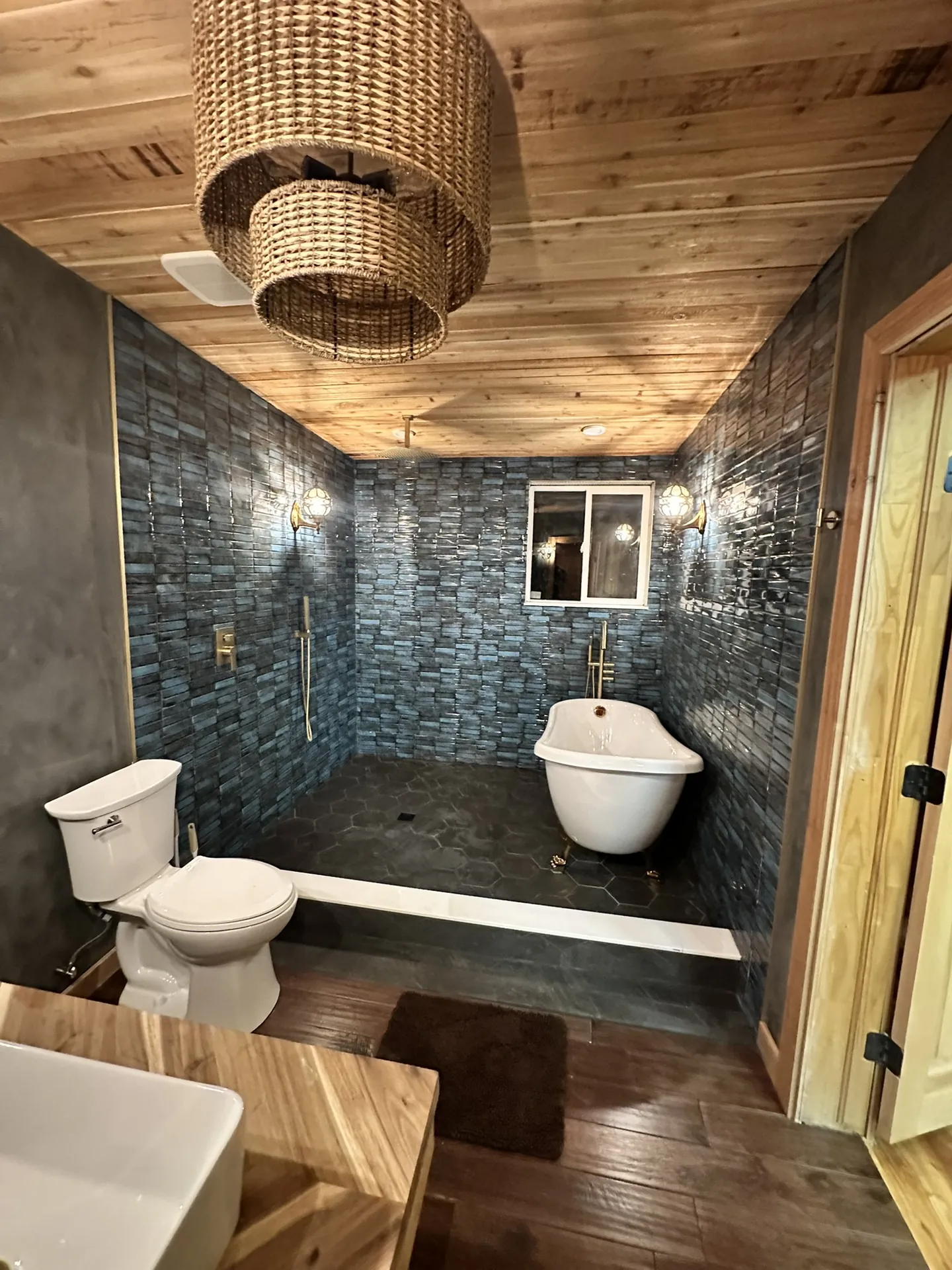 Viking Solutions structural bathroom remodel in Washington County, Utah — finished spa bathroom with freestanding clawfoot tub, blue handmade tile, cedar ceiling, and brass fixtures