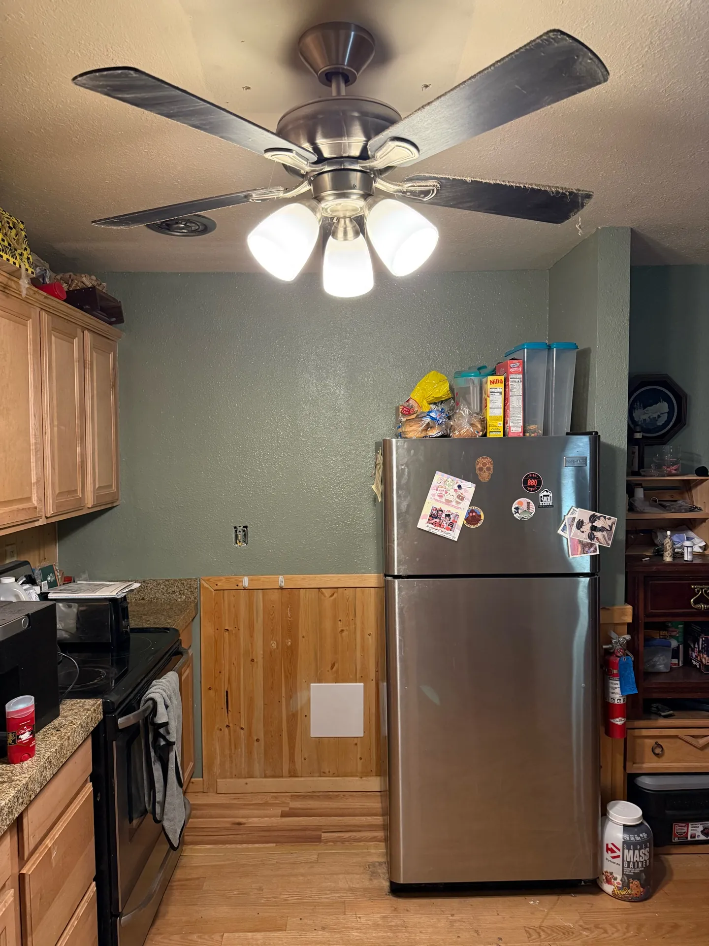 Repaired kitchen wall painted sage green with the rebuilt knotty pine wainscoting below