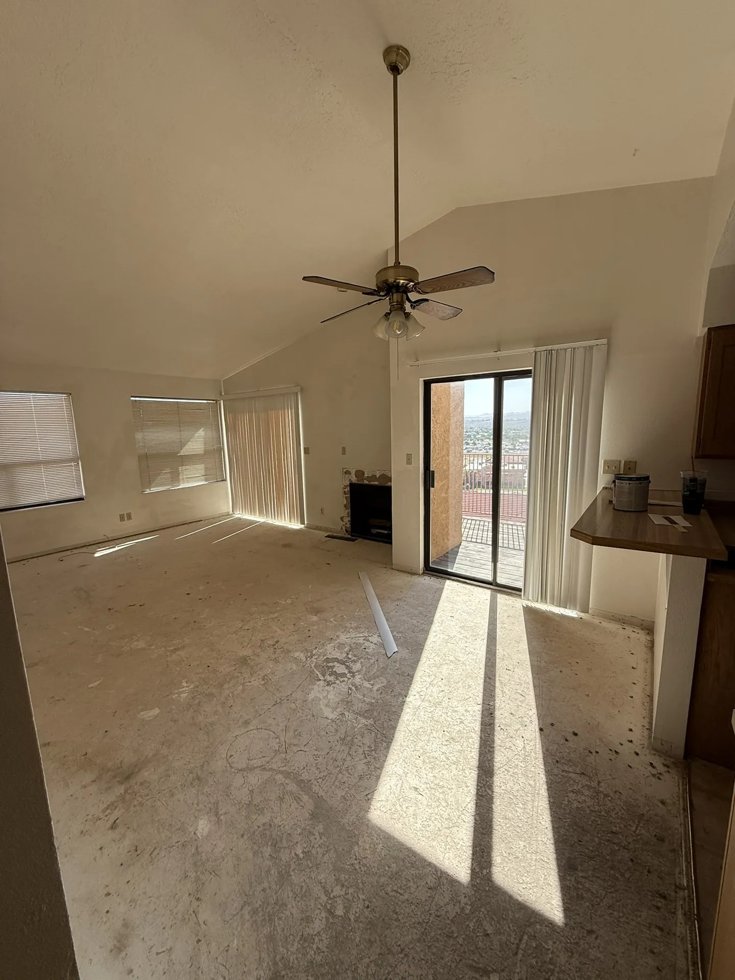 Condo living room before remodel with worn flooring and dated finishes but a large view window