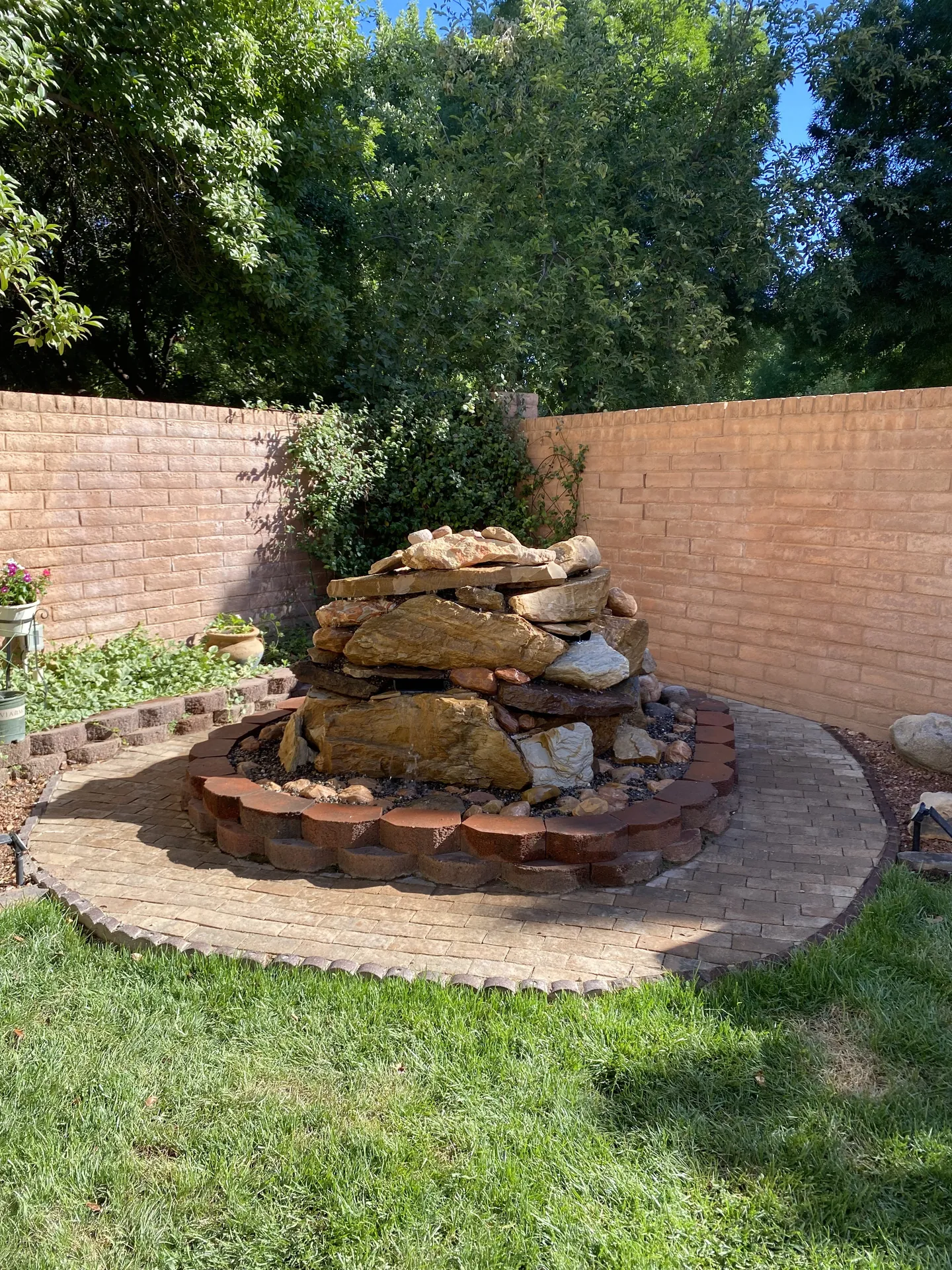 Close-up of the stacked sandstone fountain with paver border and black river rock fill