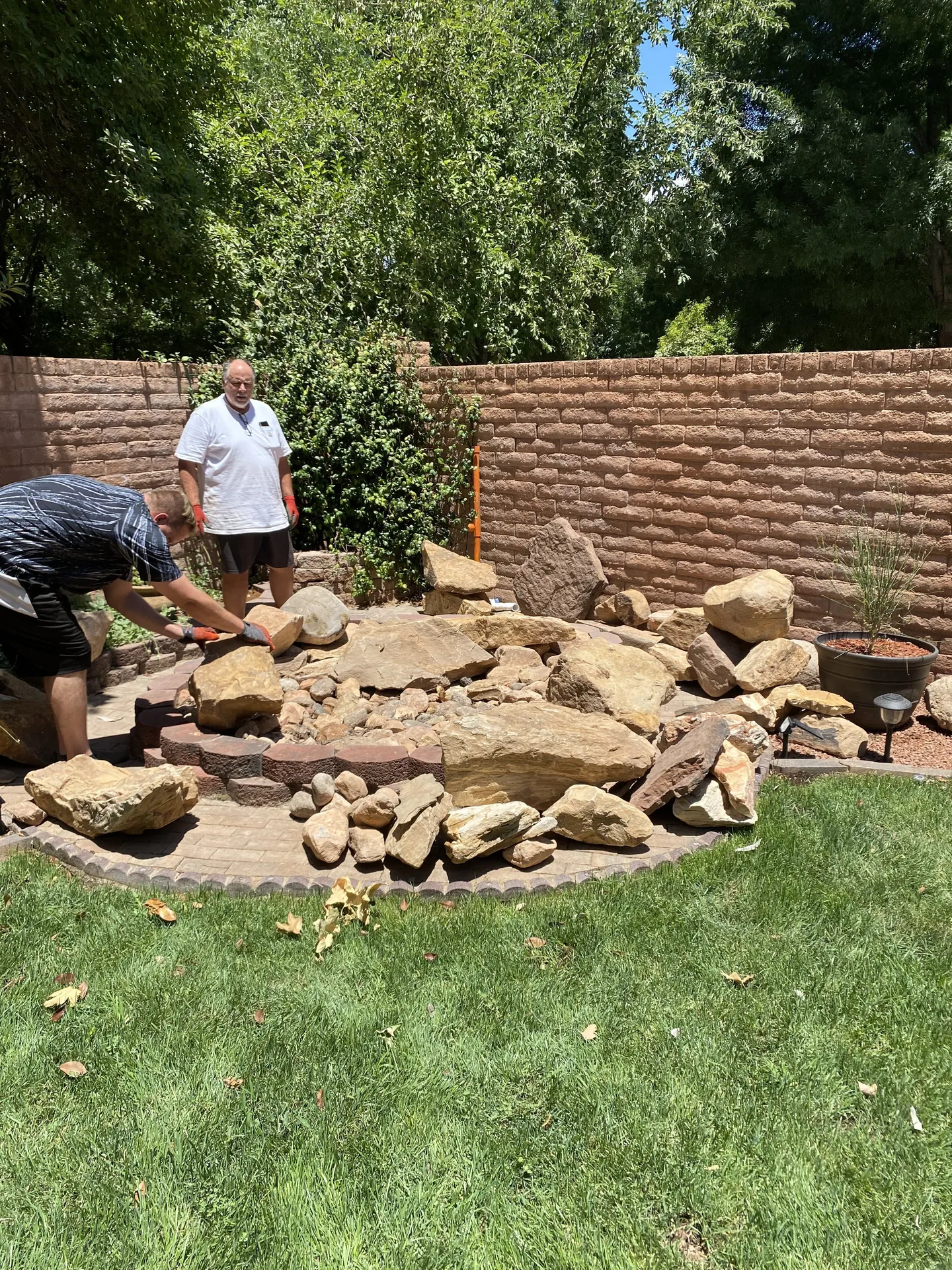 Viking Solutions crew placing and arranging large sandstone boulders on the paver pad during fountain construction