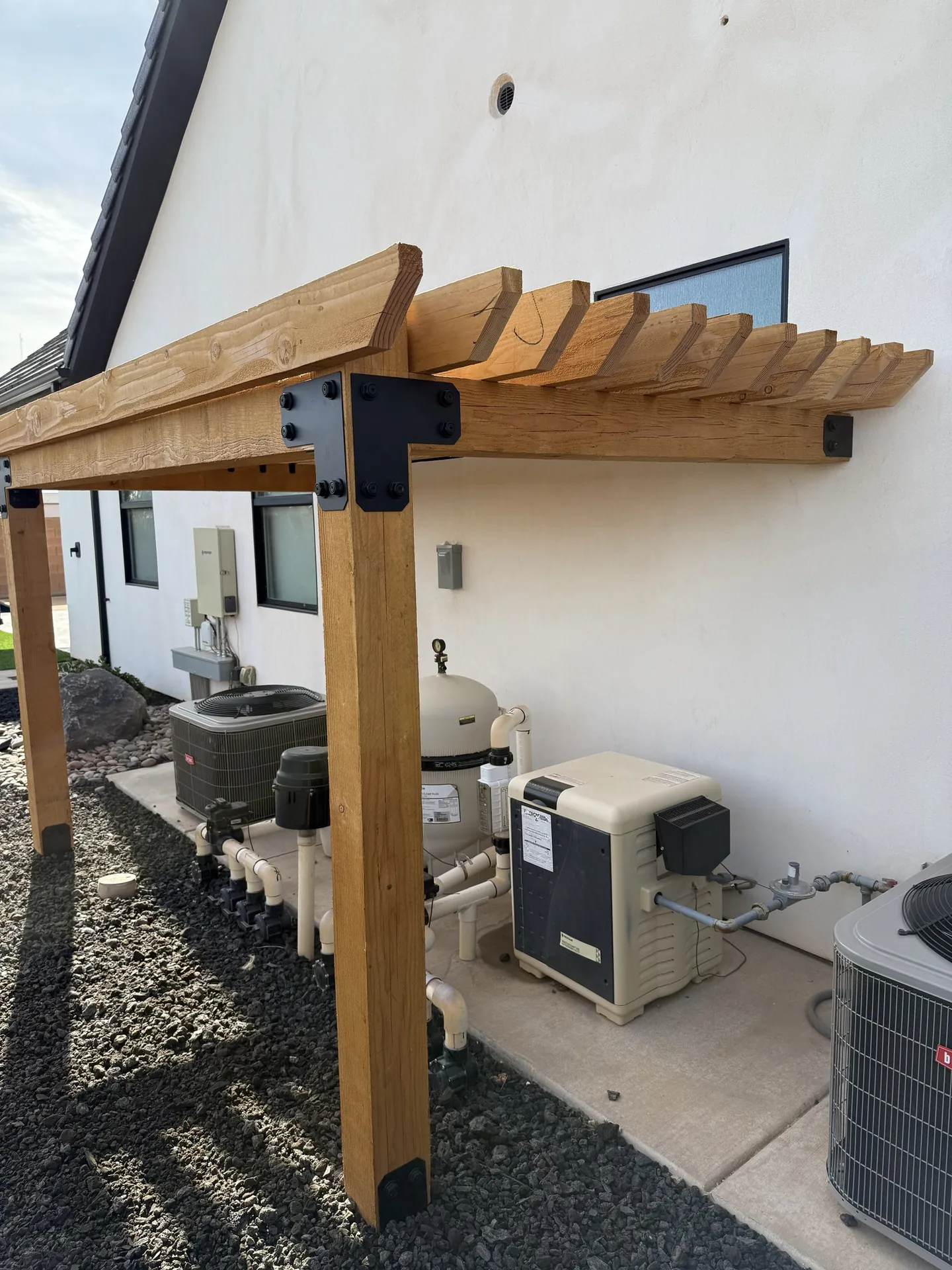 Close-up of a black powder-coated steel post base and beam bracket on the cedar pergola