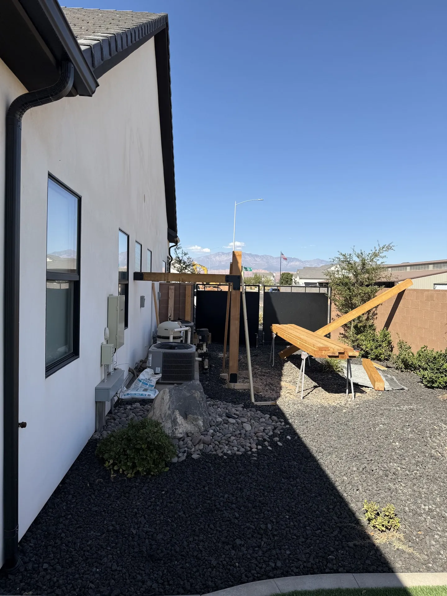 Pergola mid-construction with posts standing and beams being assembled on sawhorses