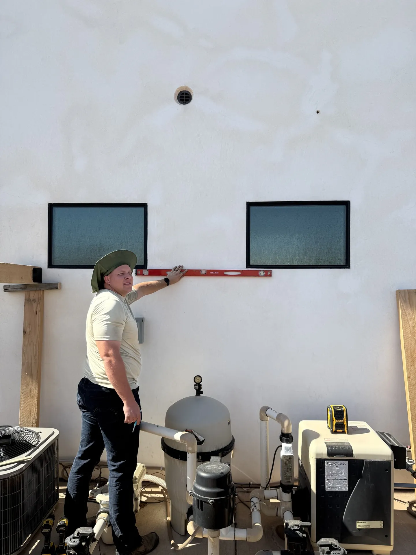 Crew member leveling the ledger reference against the house wall before post installation