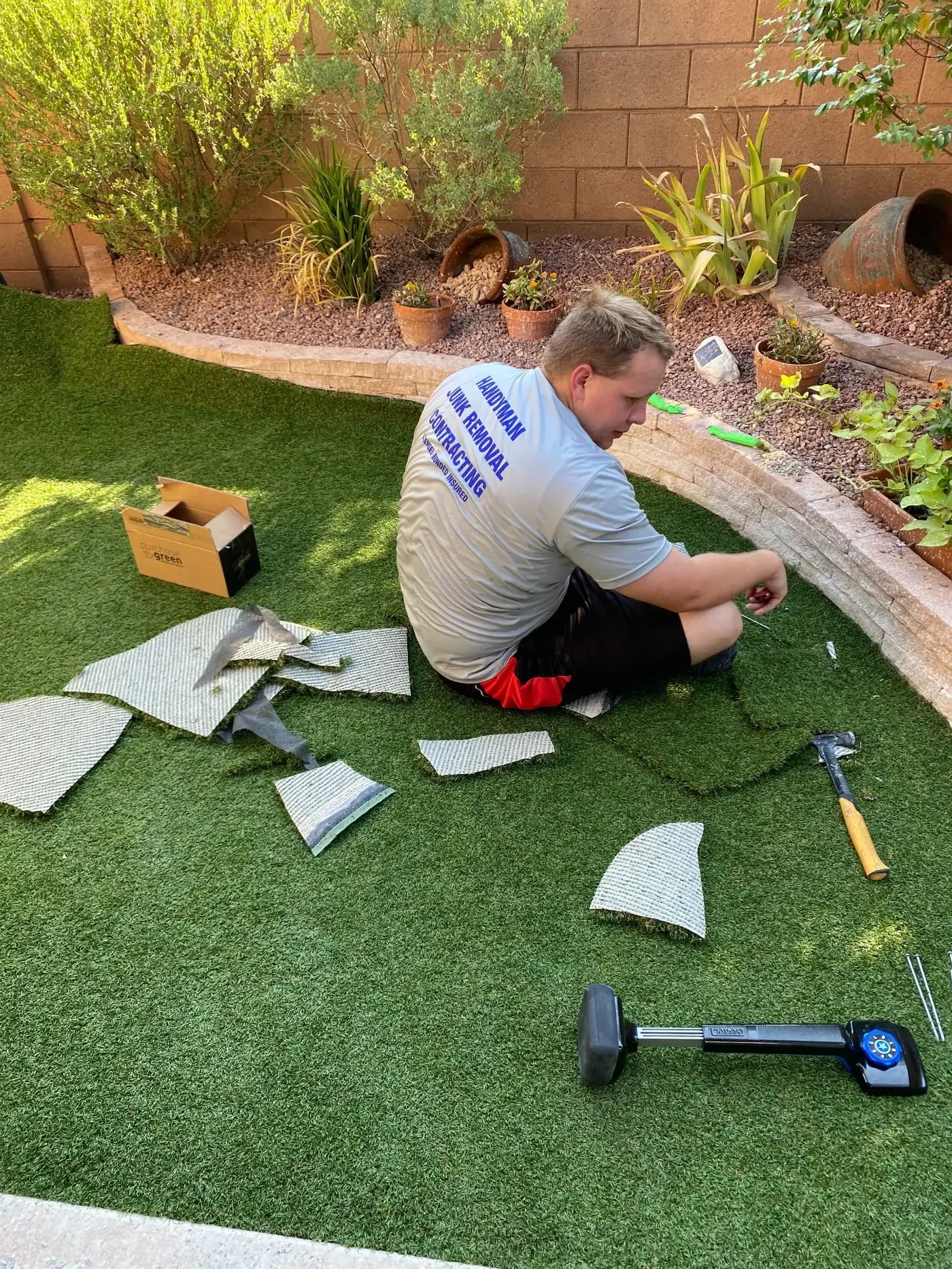 Crew member trimming turf seams and fitting the edge along the retaining wall