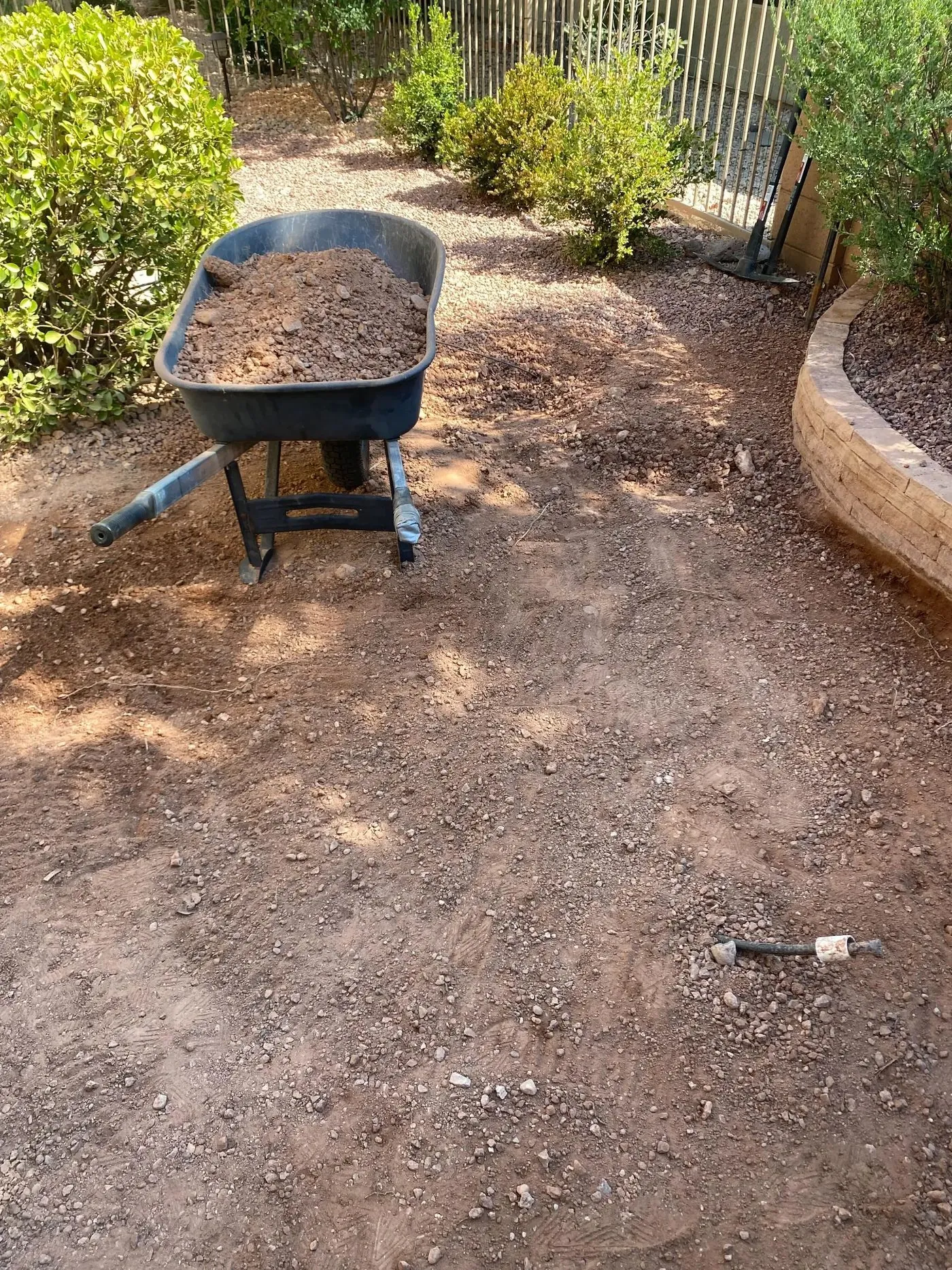 Crew excavating gravel by wheelbarrow during turf site preparation