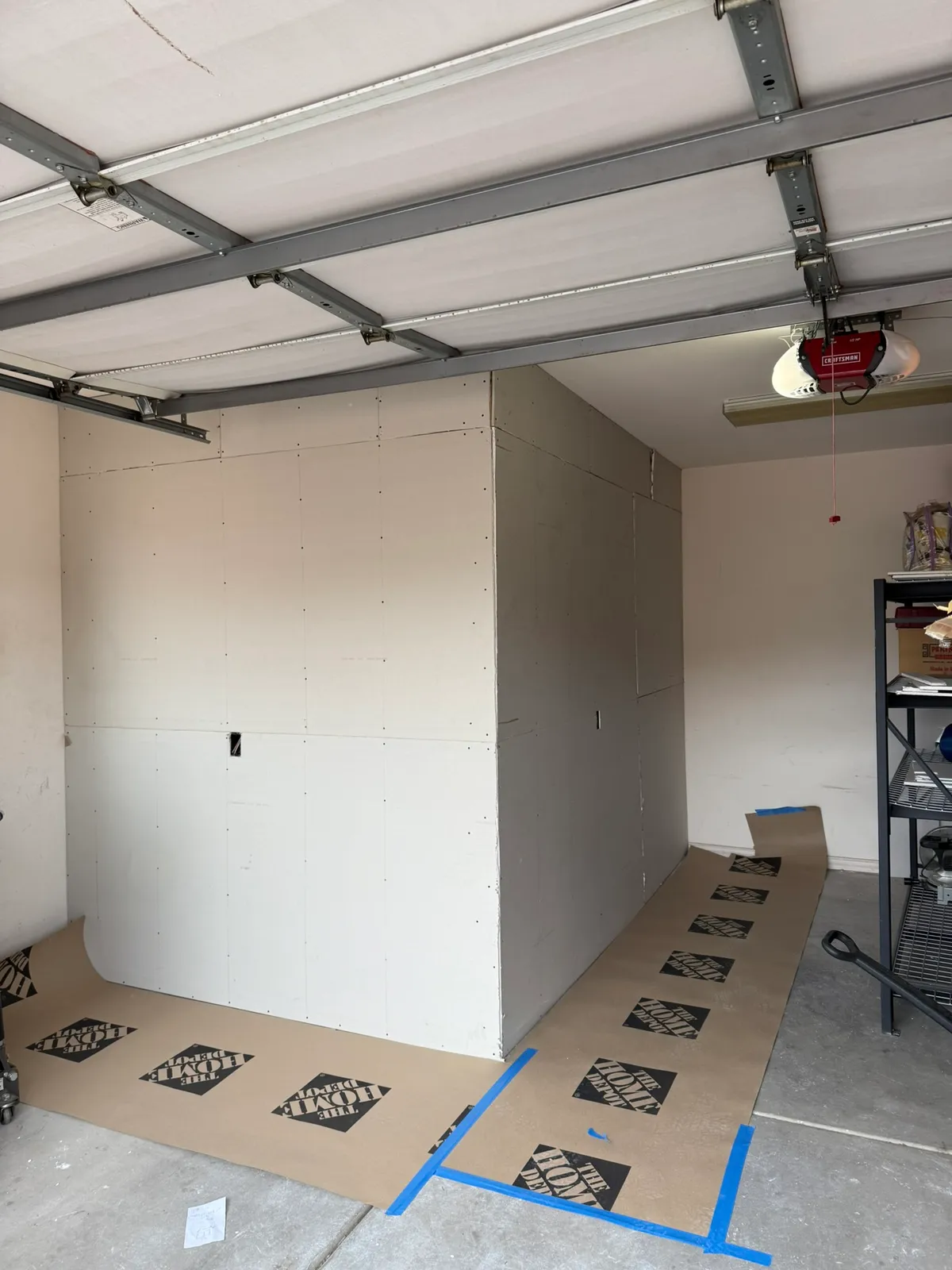 New drywall hung on a framed storage room inside a St. George garage with floor protection paper taped down
