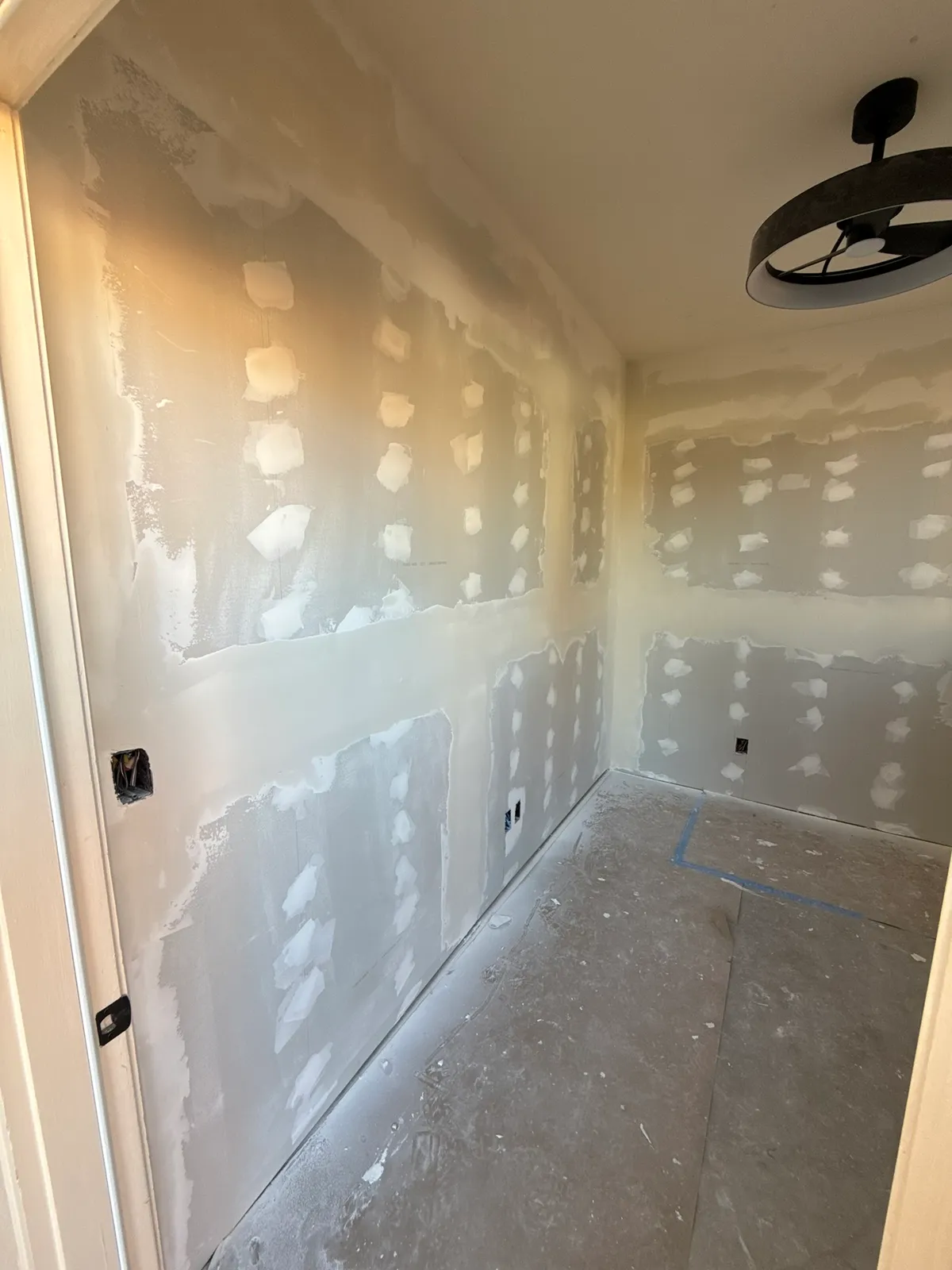 Interior of the storage room with mud coats built up on walls and ceiling and a ceiling light fixture overhead